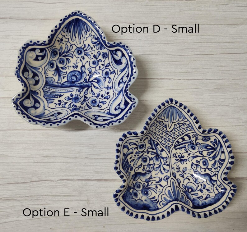 May include: Two small, white ceramic bowls with blue and white floral designs. The bowls are shaped like a leaf and have a scalloped edge. The text "Option D - Small" is above the top bowl and "Option E - Small" is below the bottom bowl.