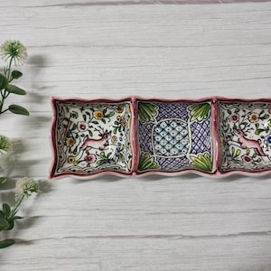 May include: A ceramic serving dish with three sections. Each section features a different floral design with a pink deer. The dish has a pink rim and a white background.