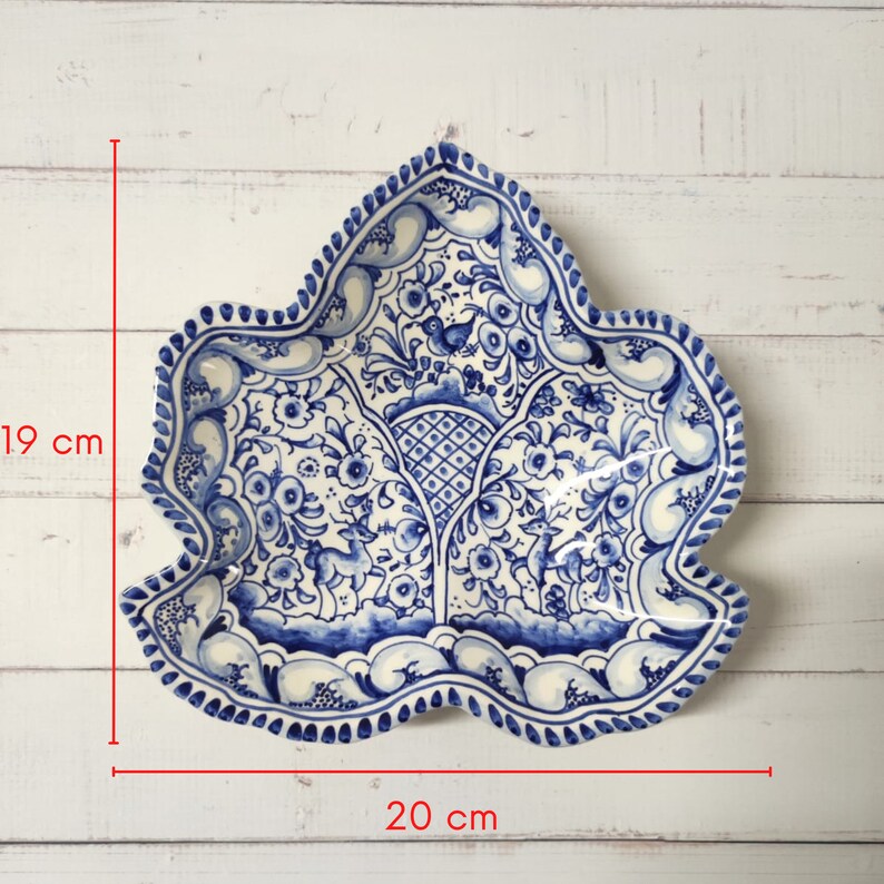 May include: A blue and white ceramic serving dish shaped like a leaf. The dish has a floral design with a blue and white border. It measures 19 inches by 20 inches.