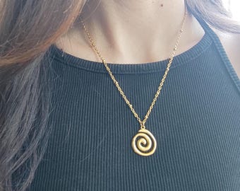 May include: A gold chain necklace with a spiral pendant. The chain is made of small, round beads.