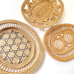 Peut inclure: Trois paniers ronds en rotin tressé avec des motifs ajourés complexes. Un panier présente un motif géométrique de triangles noirs, un autre un tressage en treillis central, et le troisième un motif de bordure en rayons.