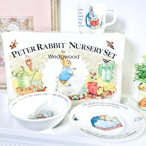 May include: A Peter Rabbit Nursery Set by Wedgwood, including a white box, bowl, plate, and mug. The set features illustrations of Peter Rabbit and other characters. The box has the text "Peter Rabbit Nursery Set".