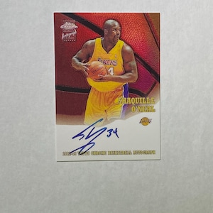 Puede incluir: Una tarjeta de baloncesto con Shaquille O'Neal con el uniforme de los Lakers, sosteniendo un balón Spalding. La tarjeta tiene una firma y el texto "2002-03 Topps Chrome Basketball Autograph."