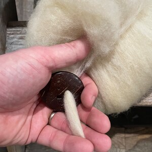 In-use photo of dis, showing wool pulled through diz to create roving.