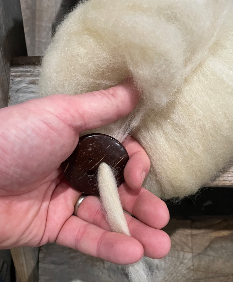 In-use photo of dis, showing wool pulled through diz to create roving.