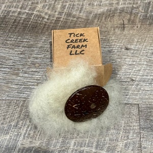 Diz shown with Gulf Coast sheep’s wool and packaging box folded and closed with Tick Creek Farm LLC printed on the top.