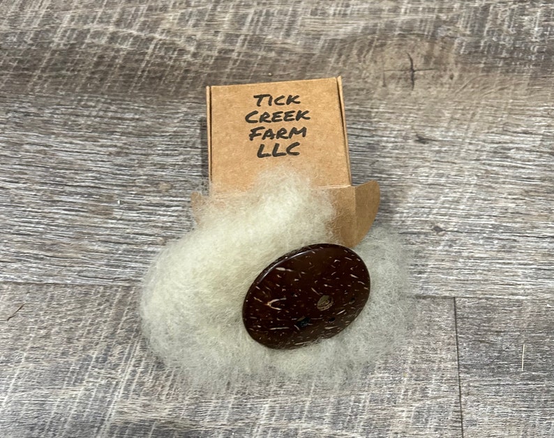 Diz shown with Gulf Coast sheep’s wool and packaging box folded and closed with Tick Creek Farm LLC printed on the top.