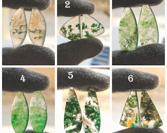 May include: Six pairs of polished gemstone cabochons are displayed. Each pair showcases distinct patterns of green, white, and brown inclusions within translucent stones. The shapes vary, including teardrop, triangular, and oval designs, ideal for jewellery making.