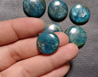 May include: A collection of polished, round gemstones in shades of teal and blue. The stones have a smooth, glossy surface with natural veining and variations in color. The gemstones are approximately 1 inch in diameter.
