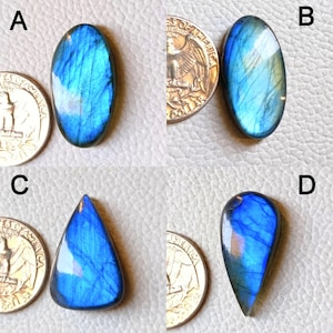 Puede incluir: Cuatro piedras preciosas de labradorita pulidas en varias formas: ovalada, ovalada alargada, triangular y en forma de lágrima. Las piedras muestran destellos iridiscentes azules y verdes. Cada piedra preciosa está junto a una moneda para comparar el tamaño.