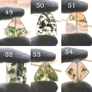 May include: Assortment of polished moss agate gemstone cabochons in various shapes, including triangles, rectangles, and diamonds. The stones display green, white, and translucent patterns. Each stone is held by a gloved hand, with numbers 49-54 visible.