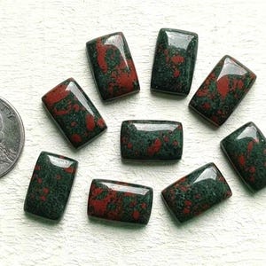 May include: A collection of rectangular gemstones with a dark green base and red inclusions. A US quarter is included for size reference. The gemstones are polished and have a glossy finish, ideal for jewelry making or collecting.