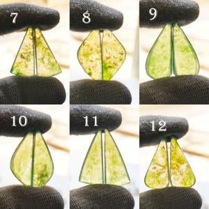 May include: A collection of six pairs of translucent, green and yellow gemstone cabochons. Each pair is held by a gloved hand, showcasing different shapes: triangles, diamonds, and teardrops. The stones have natural inclusions.