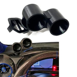 May include: A black dual gauge pod mount designed for automotive dashboards. The unit features two circular openings for gauges and an integrated mounting bracket with ventilation slats, shown both isolated and installed on a car dashboard.