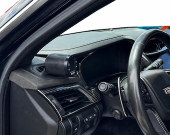 May include: Interior view of a car dashboard. A black gauge is mounted on the dashboard near the air vent. The steering wheel and other controls are visible. The dashboard is black with carbon fiber accents.