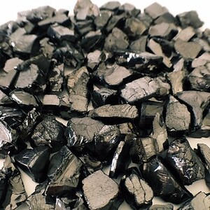 May include: A pile of black obsidian chips, a type of volcanic glass, used for crafting and jewelry making.