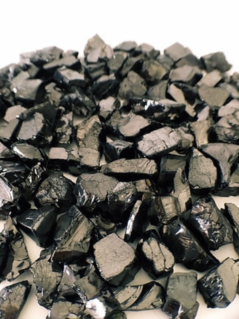 May include: A pile of black obsidian chips, a type of volcanic glass, used for crafting and jewelry making.