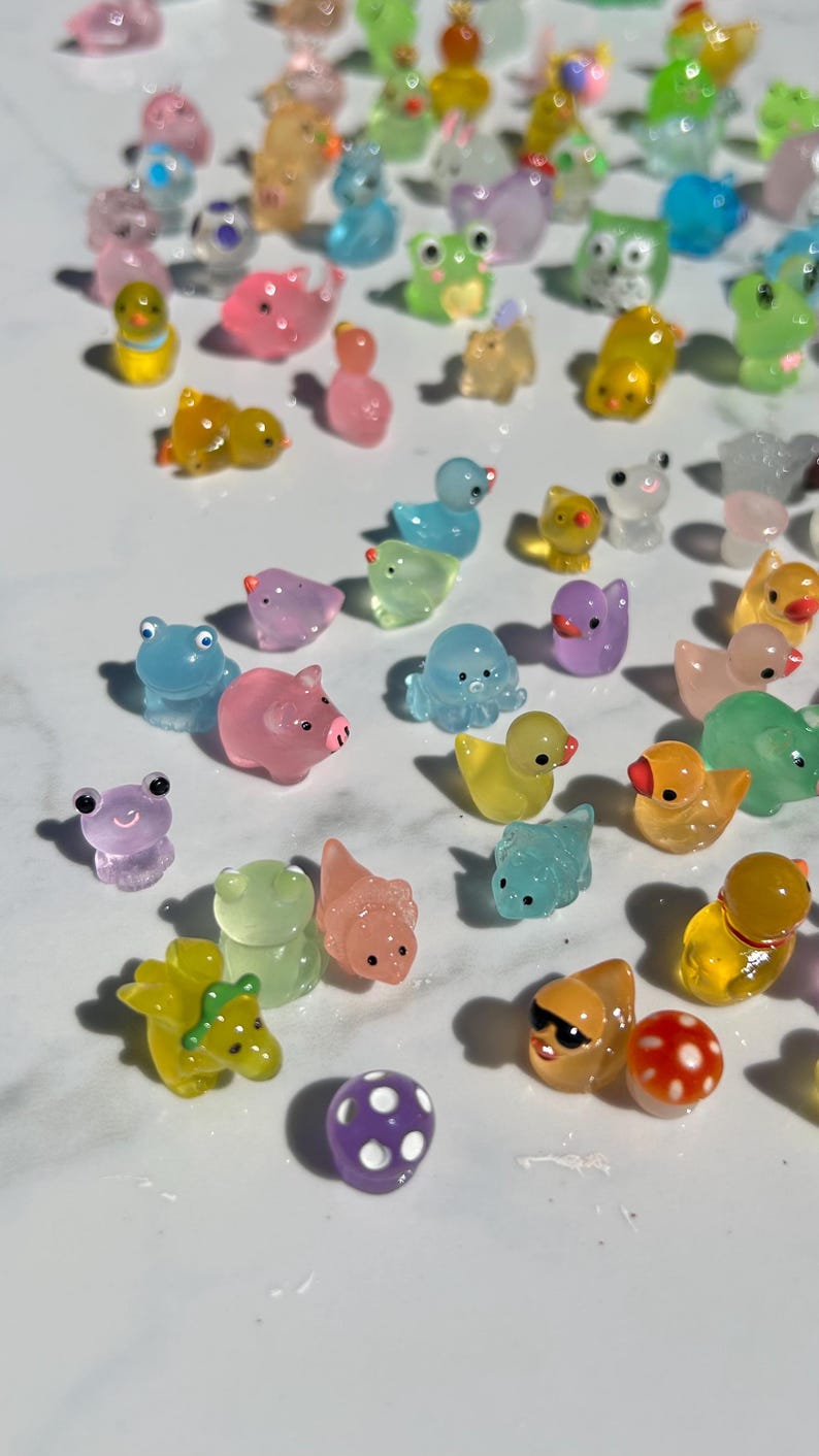 May include: A collection of colorful, translucent, miniature animal figurines. The figurines are made of a jelly-like material and feature a variety of animals, including a pig, a frog, a duck, an octopus, and a dinosaur.