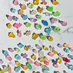 May include: A collection of colorful, translucent animal figurines. The figurines are made of a jelly-like material and feature a variety of animals, including frogs, pigs, ducks, and fish.