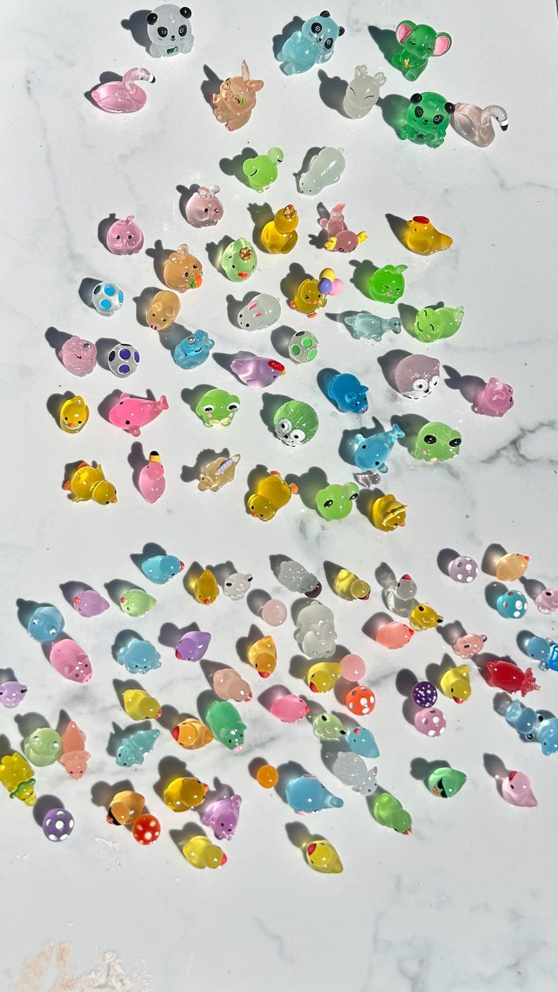 May include: A collection of colorful, translucent animal figurines. The figurines are made of a jelly-like material and feature a variety of animals, including frogs, pigs, ducks, and fish.