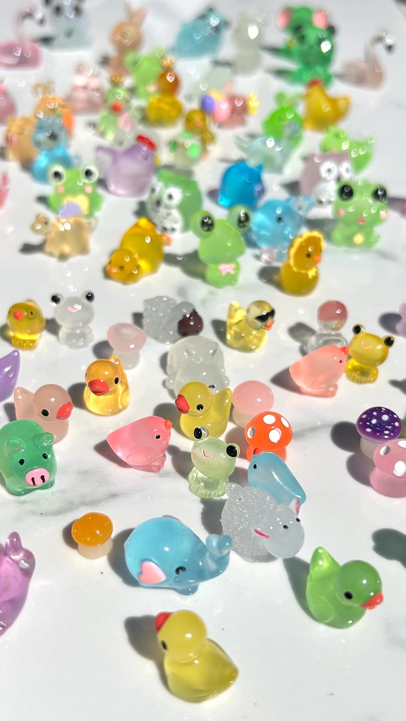 May include: A collection of colorful, miniature animal figurines made of clear plastic. The figurines include a variety of animals, such as ducks, frogs, pigs, elephants, and birds. The figurines are all about 1 inch tall and are perfect for adding a touch of whimsy to any space.