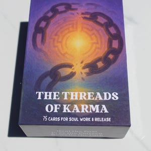 May include: A deck of "The Threads of Karma" cards. The box features a purple and blue background with a broken chain graphic. Text on the box reads "75 Cards for Soul Work & Release".