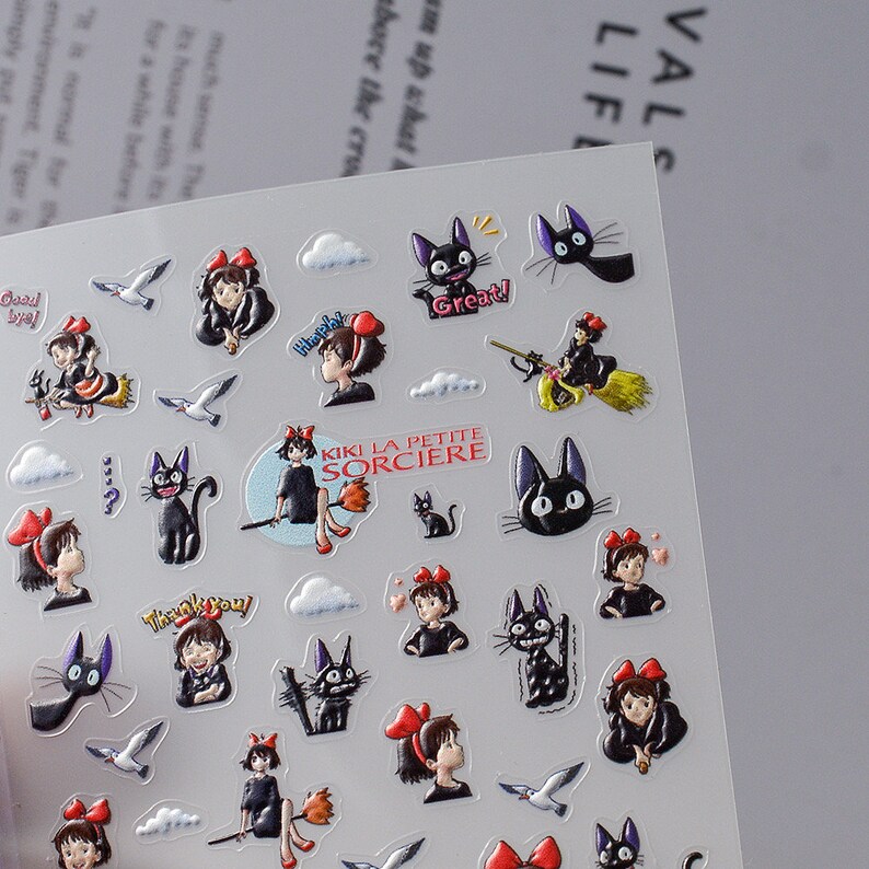 May include: A sheet of stickers featuring characters from the animated film Kiki's Delivery Service. The stickers feature Kiki, Jiji the black cat, and other characters from the film. The stickers are printed on clear vinyl and are perfect for decorating laptops, water bottles, and other surfaces.