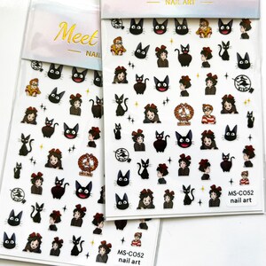May include: Two sheets of nail art stickers featuring a black cat with a red bow, a girl with a red bow, and a boy with a red and white striped shirt. The stickers are on a white background with gold lettering that says "Meet Nail" and "Nail Art".