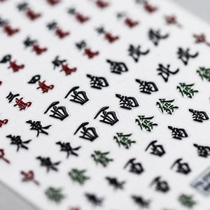 May include: A sheet of stickers featuring a variety of Japanese characters in black, green, and red. The characters are printed on a transparent background.