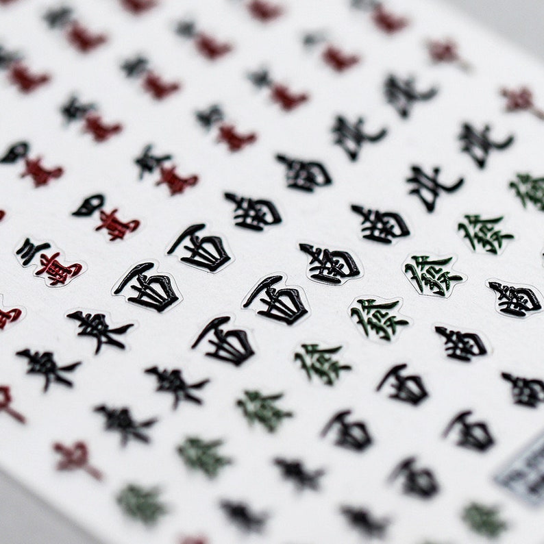May include: A sheet of stickers featuring a variety of Japanese characters in black, green, and red. The characters are printed on a transparent background.