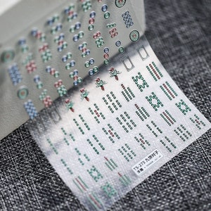 May include: A sheet of clear nail stickers with various designs, including circles, lines, and a bird. The stickers are labelled "TS-275 九饼对子 TENSOR".
