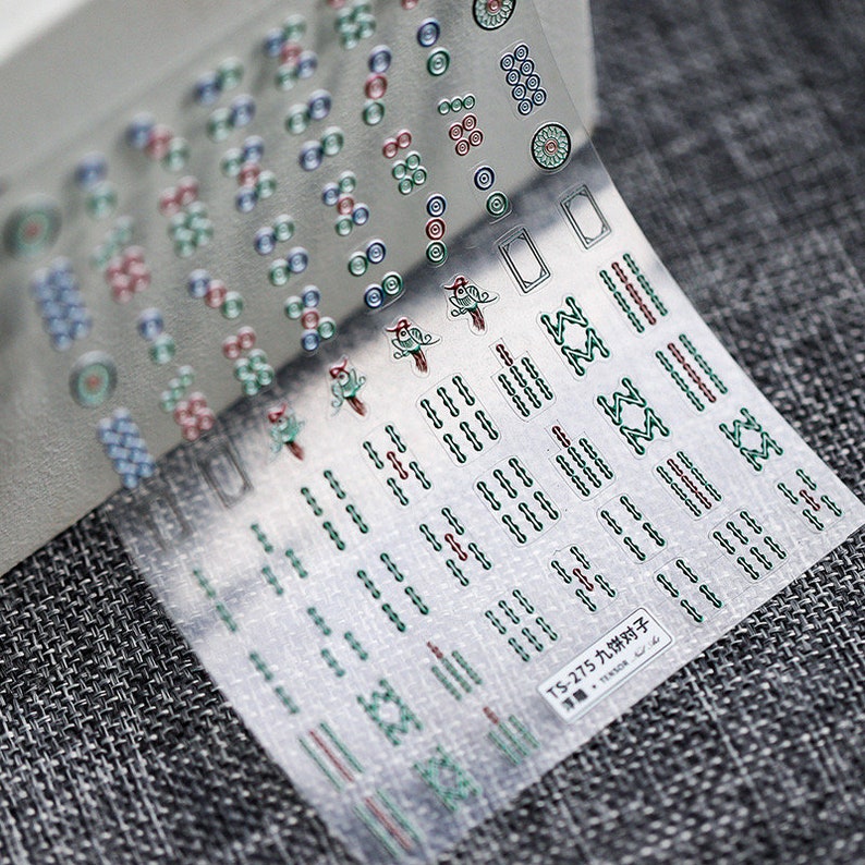 May include: A sheet of clear nail stickers with various designs, including circles, lines, and a bird. The stickers are labelled "TS-275 九饼对子 TENSOR".