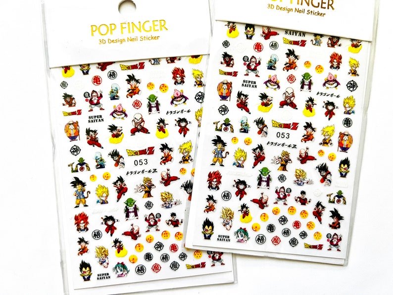 Pu&ograve; includere: Un foglio di adesivi 3D per unghie con personaggi della serie anime Dragon Ball Z. Gli adesivi sono su sfondo bianco e presentano vari personaggi, tra cui Goku, Vegeta e Gohan. Gli adesivi sono etichettati con "053" e "Dragon Ball Z".