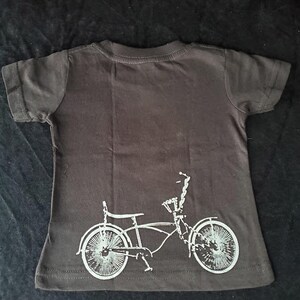 May include: A black t-shirt with a white silhouette of a bicycle on the back.