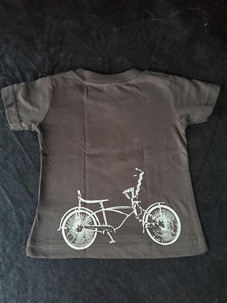 May include: A black t-shirt with a white silhouette of a bicycle on the back.