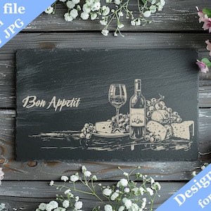 May include: A black slate board with a design of a bottle of wine, a glass of wine, cheese, and grapes. The text "Bon Appetit" is written on the board. The board is surrounded by white and pink flowers.