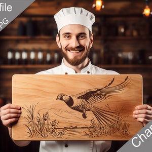 May include: A wooden cutting board with a laser-engraved design of a pheasant in flight. The board is held by a chef wearing a white chef's hat. The text "Charcuterie design" is visible in the lower right corner of the image.