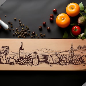 Può includere: Un tagliere di legno con un design inciso di uva, vino e una scena di campagna. Il testo "Charcuterie design" è stampato nell'angolo in basso a destra del tagliere.