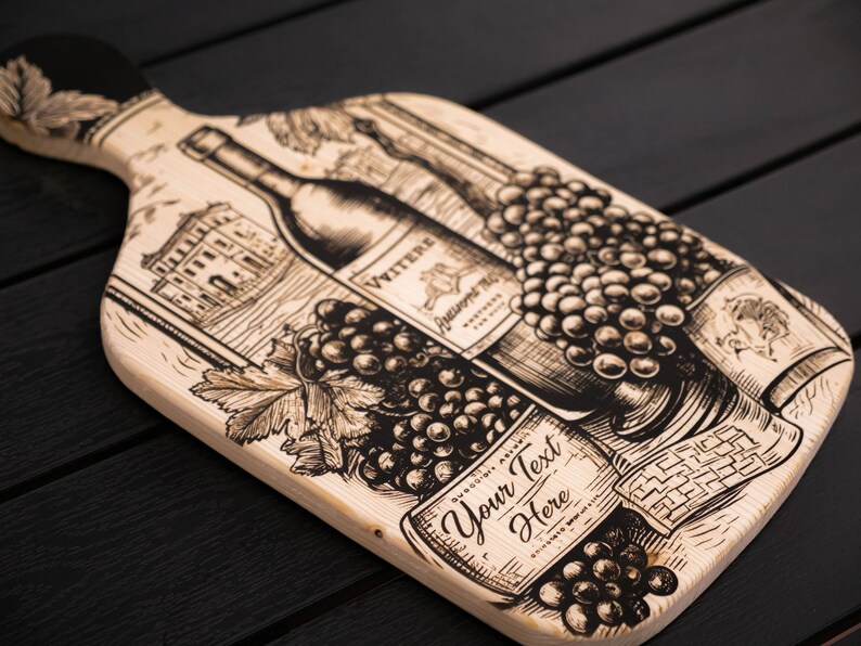 May include: A wooden cutting board with a black and white illustration of wine bottles, grapes, and a building. The text "Your Text Here" is printed on the board.