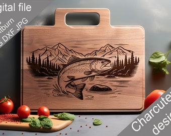 May include: A wooden cutting board with a handle features a laser-engraved design of a trout jumping out of the water in front of a mountain range and pine trees. The text "Charcuterie design" is printed on the bottom right corner of the board.