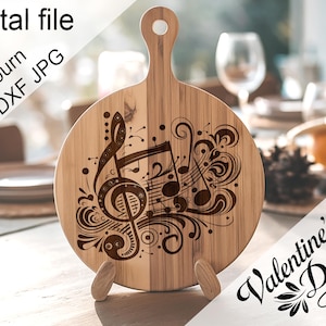 May include: A wooden cutting board with a design of musical notes and swirls. The board has a handle and is standing on a table. The text "Valentine's Day" is written in a decorative font on a white background.