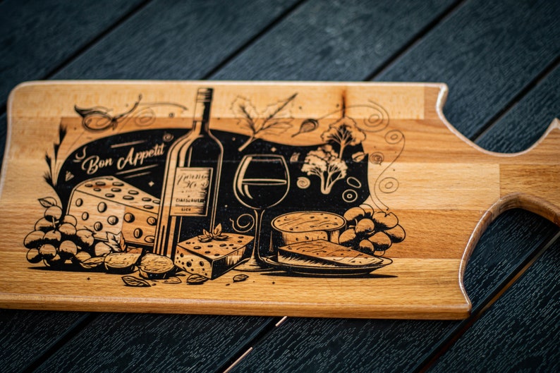 May include: A wooden cutting board with a black and white design of a wine bottle, a glass of wine, cheese, grapes, and the text "Bon Appetit".