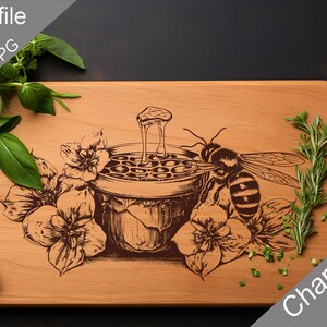 May include: A wooden cutting board with a laser-engraved design of a bee collecting honey from a honeycomb. The design is surrounded by flowers and leaves. The text "Charcuterie design" is engraved in the bottom right corner of the board.