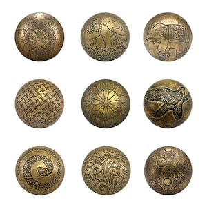 May include: A collection of nine round brass cabinet knobs, each featuring a unique engraved design. Patterns include an elephant, a soaring bird, a woven texture, a floral mandala, swirling scrolls, and geometric circular motifs in antique brass.