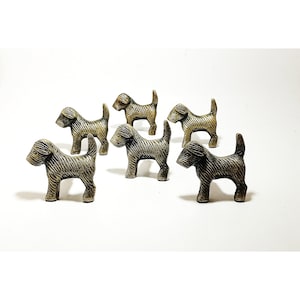 Peut inclure: Six petites figurines de chien en métal de couleur dorée. Les chiens sont tous tournés dans la même direction et présentent un motif texturé rayé.