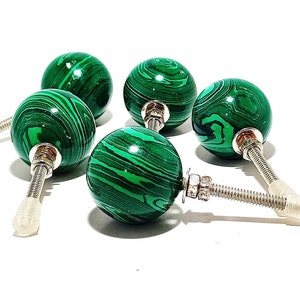Pode incluir: Seis puxadores de armário redondos com acabamento em malaquite polida. Cada puxador apresenta um padrão vibrante de redemoinho verde e preto. Os puxadores têm ferragens de metal prateado e uma fixação de parafuso de plástico transparente.