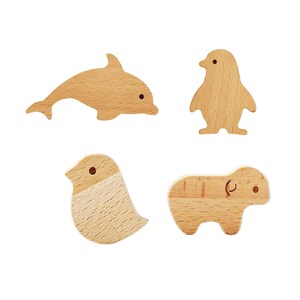 May include: Four wooden animal cutouts: a dolphin, a penguin, a bird, and a small mammal. Each cutout is made of light-colored wood with simple, rounded shapes and small, dark dots for eyes. The dolphin is swimming, the penguin is standing, the bird is perched, and the mammal is walking.