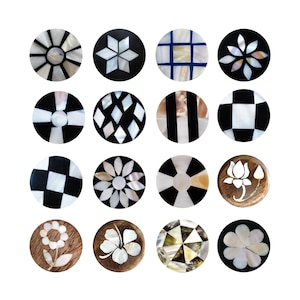 May include: A collection of sixteen round decorative objects with inlaid designs. The designs include floral patterns, geometric shapes, and checkered patterns. The objects are made of wood and mother-of-pearl, with a mix of black, white, and natural wood tones.