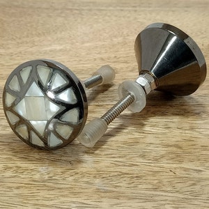 Peut inclure: Deux boutons de cabinet noirs avec un motif en nacre blanche. Les boutons ont une base ronde et une tige à visser.