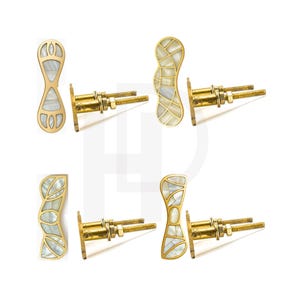Könnte beinhalten: Satz dekorativer Türgriffe aus Messing mit Perlmutt-Inlay. Jeder Griff hat ein einzigartiges Design mit Gold-Finish und dekorativem Inlay aus weißen und irisierenden Muschelteilen. Inklusive Befestigungsmaterial.